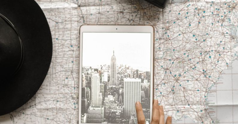 City Map - Flat Lay Photography of Person Touching Silver Ipad on World Map Chart Beside Black Hat