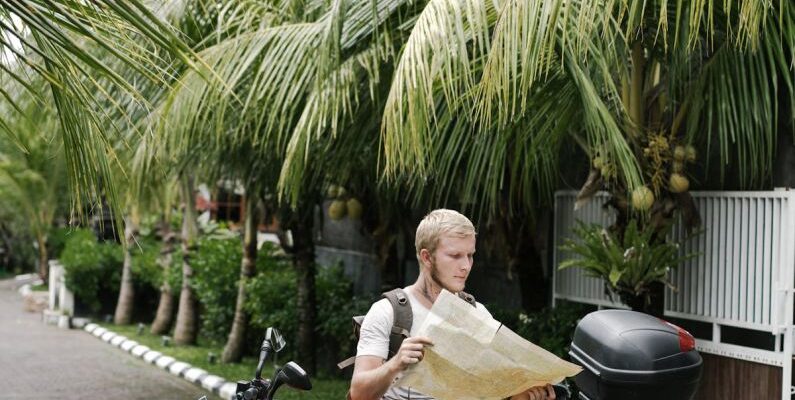 Map - Focused man studying map leaning on motorbike