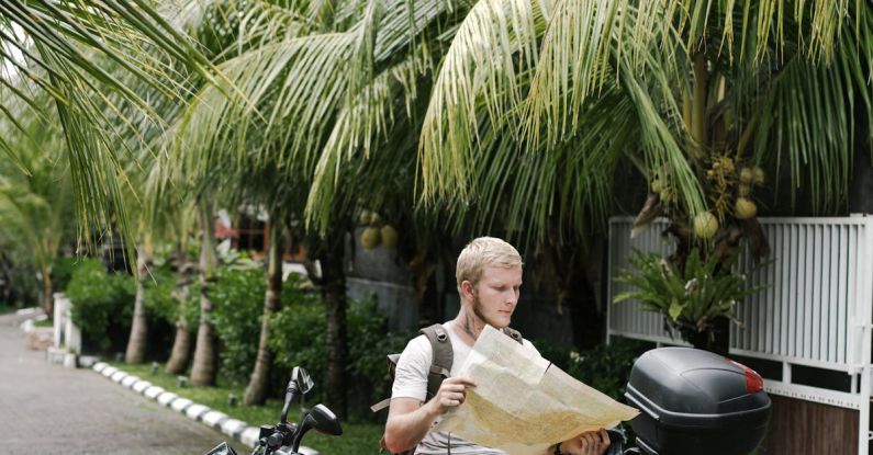 Map - Focused man studying map leaning on motorbike