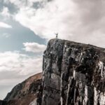 Elevation - Scenic Photo of Man Standing on Cliff Edge