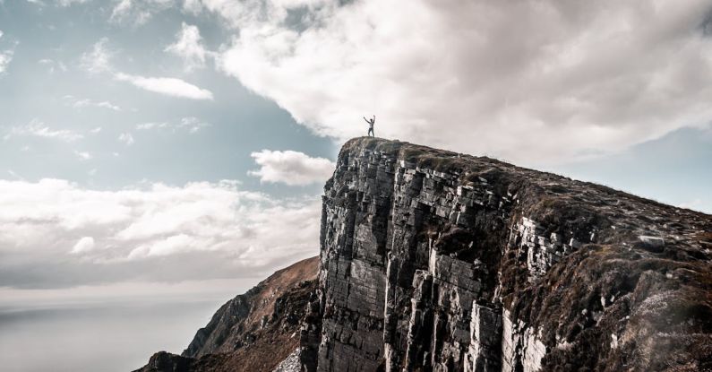 Elevation - Scenic Photo of Man Standing on Cliff Edge