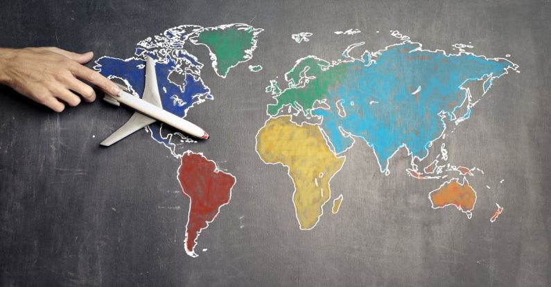 Population Density Map - Top view of crop anonymous person holding toy airplane on colorful world map drawn on chalkboard