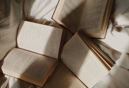 Spatial Literacy - From above opened paper books placed on comfortable bed with white disheveled sheets in daylight