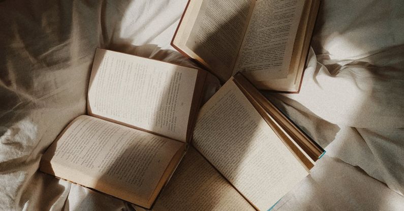 Spatial Literacy - From above opened paper books placed on comfortable bed with white disheveled sheets in daylight