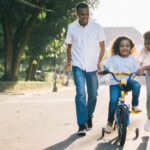 Teaching Methods - Man Standing Beside His Wife Teaching Their Child How to Ride Bicycle