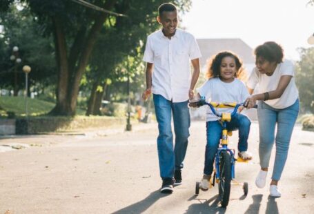 Teaching Methods - Man Standing Beside His Wife Teaching Their Child How to Ride Bicycle