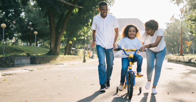 Teaching Methods - Man Standing Beside His Wife Teaching Their Child How to Ride Bicycle